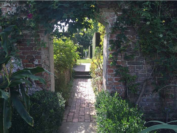 Archway through walled gardens, climbing plants and herbaceous borders at Sissinghurst gardens